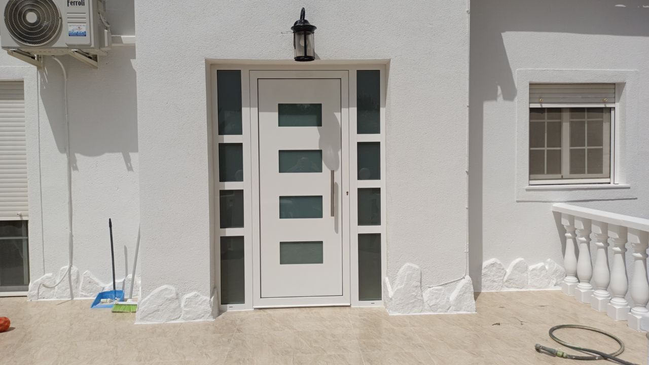 Puerta de entrada de aluminio con fijos laterales acristalados