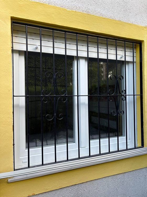 Zweiflügeliges Kunststofffenster hinter einem Gitter